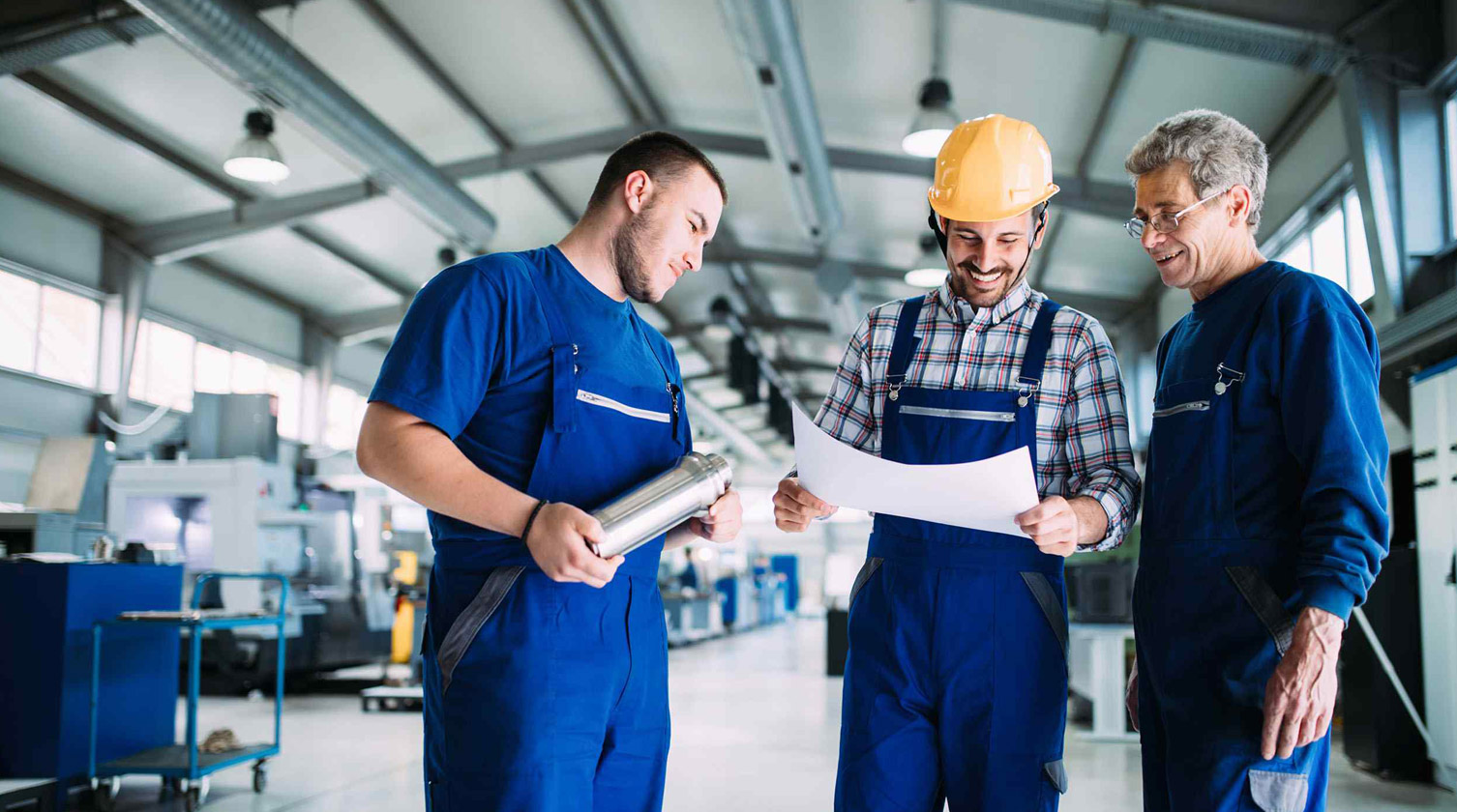 Team di tecnici specializzati che collaborano alla revisione di un disegno tecnico in fabbrica